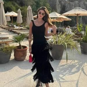 Robe noire élégante sans manches avec ourlet à franges multicouches au bord de la mer