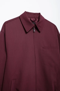 Detailed view of the metal zipper and chest pocket on this burgundy women's jacket