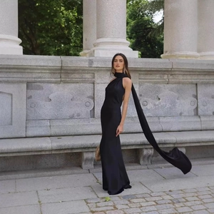Detail of elegant black satin halter neck dress with long draping ribbon streamers