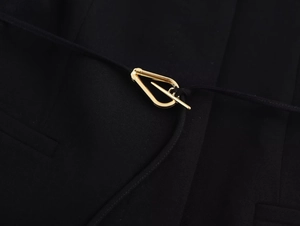 Detailed view of black woven suit fabric with minimalist golden metal buckle hardware