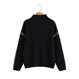 Detail of high neck black chunky knit sweater featuring white contrast hand stitching