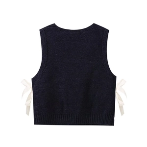 Detailed view of navy knit vest with elegant side white ribbon bows and ribbed hemline