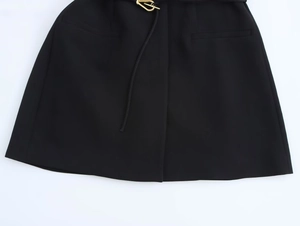 Detail of black formal skirt with front pleat and slim belt with gold V-shape buckle
