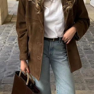 Detail view of brown suede coat with high waist denim jeans and vintage leather handbag