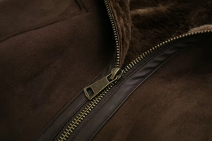 Detailed macro view of vintage bronze zipper on high-quality dark brown suede jacket