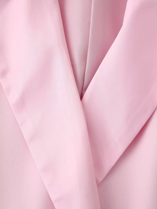Detailed close-up of pink satin suit blazer lapel showing fine fabric texture