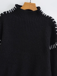 Detail of high neck black sweater with white contrast thick thread stitching on shoulder