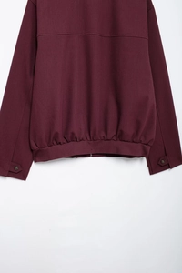 Detail of the elastic hem and buttoned cuffs on a burgundy zip-up jacket for women