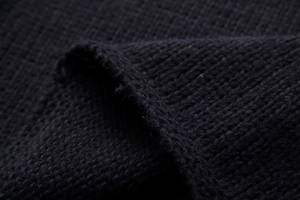 Close-up of thick black chunky knit fabric texture showing detailed weave patterns