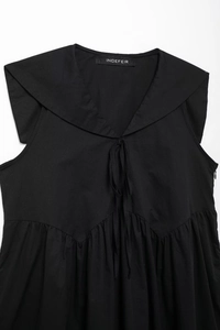 Close-up of black sleeveless dress featuring a V-neckline with ties and a large shawl collar