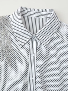 Detail view of silver beaded fringe and striped fabric on a women's button-down shirt