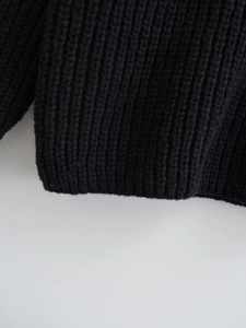 Detailed view of the black rib-knit texture and hemline on this oversized sweater