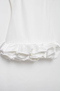 Detail view of white dress showing silky fabric texture and layered ruffle hemline