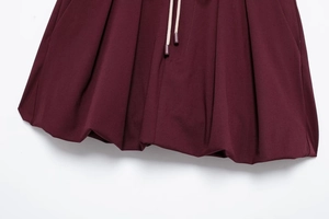 Detail view of wine red pleated fabric texture and matching drawstring on skirt