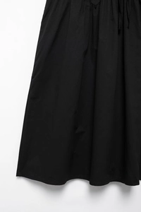 Detail of elegant black pleated dress fabric showing high-quality woven texture and drape