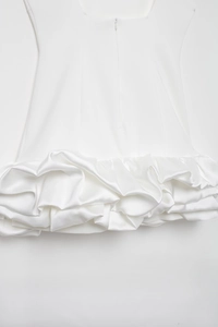 Detail of white satin dress featuring an invisible zipper and layered ruffle hemline