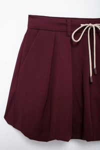 Detailed view of burgundy high-waisted pleated skort with beige cotton drawstring ties