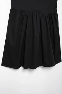 Detail of the elegant black dress featuring refined arc waistline and pleating details