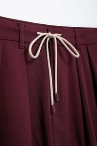 Detail of burgundy waist with beige drawstring and high-quality stitching on mini skirt