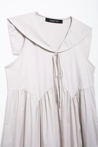 Détail de robe midi grise sans manches avec col en V, nœud et détails multicouches