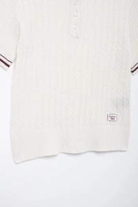 Detail of white cable knit polo top showing red cuff stripes and California embroidery