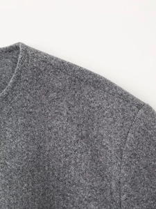 Detailed macro view of dark grey wool blend fabric texture and stitching on jacket