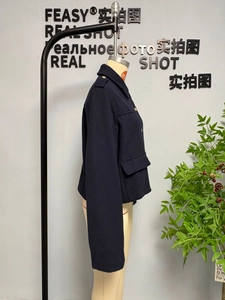 Detail view of a navy wool cropped jacket featuring gold buttons and large flap pockets