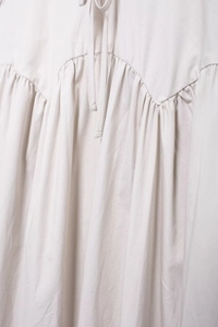 Détail de robe midi beige clair avec col à nœud et détails de taille plissée