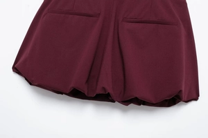 Detail view of burgundy bubble hem mini skirt with double welt pockets and woven texture
