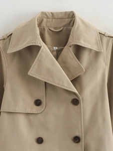 Close-up of khaki double-breasted trench coat showing lapels, epaulettes, and dark buttons