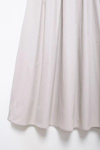 Vue détaillée d'une robe midi gris clair montrant la texture du tissu et l'ourlet de qualité