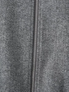 Detailed macro view of a silver metal zipper on grey soft fleece jacket fabric
