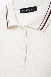 Detail of off-white ribbed knit polo shirt featuring navy collar stripes and white buttons
