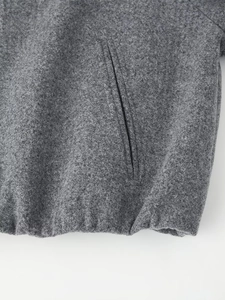 Detailed view of grey wool jacket side pocket and high-quality hem stitching craftsmanship