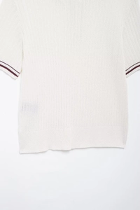Detailed close-up of ribbed white knit polo top with classic burgundy striped cuffs