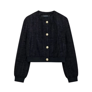 Détail d'une veste courte en tweed noir avec boutons dorés et bordures en tricot