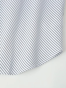 Detail of the striped shirt showing the fine pinstripe fabric and the curved hem stitching
