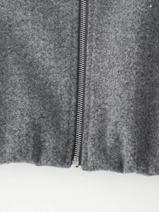 Close-up detail of silver metal zipper on dark grey wool jacket textured fabric