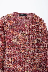 Detail of red tweed knit cardigan with textured weave and gold relief metal buttons