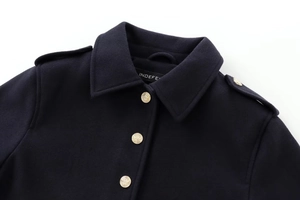 Close-up of golden crest buttons and epaulet detail on navy wool jacket coat