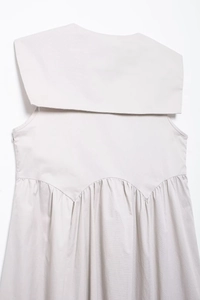 Détail du col marin et des coutures plissées au dos d'une robe midi beige sans manches