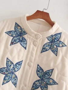 Detail of cream quilted jacket featuring floral star patches and fabric covered buttons