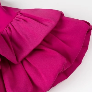 Détail de volants superposés sur le tissu d'une robe rose fuchsia à épaules dénudées