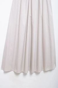 Vue détaillée des plis fins et du tissu drapé de haute qualité sur une robe midi grise