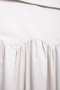 Détail des plis fins et des coutures courbées sur une robe midi beige clair