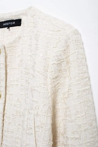 Gros plan sur le tissu en tweed texturé avec étiquette tissée et boutons dorés