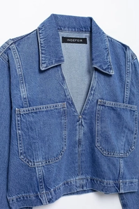 Detail of blue denim cropped shirt with V-neckline and large front pockets