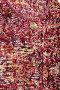 Close-up of red tweed knit fabric texture with vintage gold buttons and frayed edges