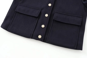 Detail view of dark blue soft jacket featuring large flap pockets and gold crest buttons