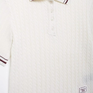 Women's cable knit polo shirt in white with red striped collar and 1986 patch